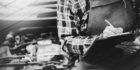 Car mechanic checking a car engine and writing on clipboard, geometric patternの写真素材