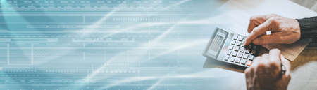 Male hand using a calculator, closeup; panoramic banner