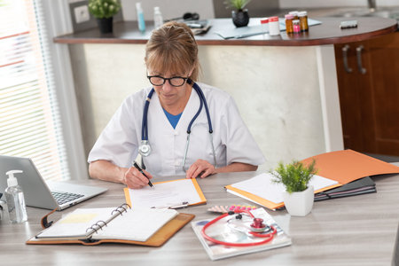 Female doctor reading a clinical record in medical officeの写真素材