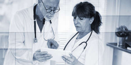 Two mature doctors discussing about medical report on digital tablet, geometric patternの写真素材