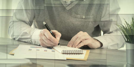 Businessman working on financial results and taking notes on notepad, geometric patternの写真素材