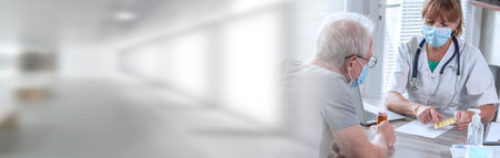 Female doctor showing medication to senior man patient; both are wearing a protective medical mask; medical consultation during coronavirus outbreak; panoramic bannerの写真素材