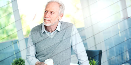 Portrait of senior businessman sitting on his desk in office, geometric pattern