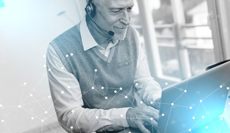 Senior businessman talking on a headset and using a laptop; light-effect
