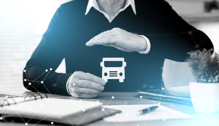 Insurer protecting a paper bus with his hand; light-effectの写真素材