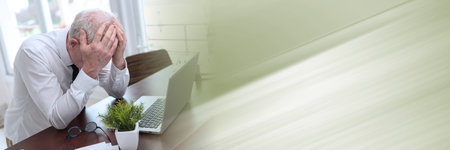 Stressed businessman sitting in office with head in hands; panoramic bannerの写真素材