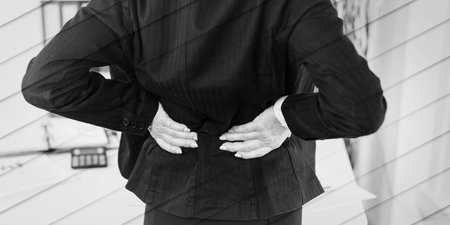 Businesswoman suffering from back pain at office, geometric patternの写真素材