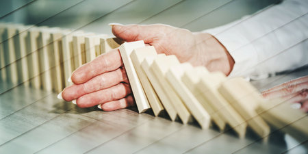 Female hand stopping domino effect. concept of business control, geometric pattern