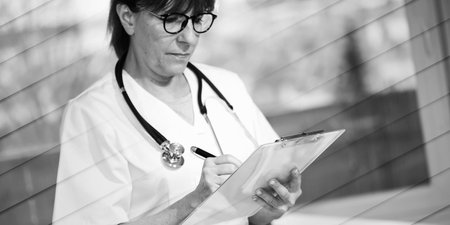 Female doctor taking notes on clipboard in medical office, geometric patternの写真素材