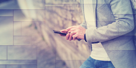 Man standing against a wall and using mobile phone, outdoors, geometric patternの写真素材