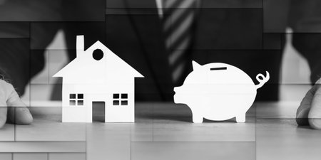 Businessman sitting in front of a paper piggy bank and a paper house, geometric patternの写真素材