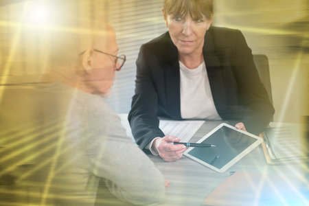 Female financial adviser giving information on digital tablet to her client; multiple exposureの写真素材