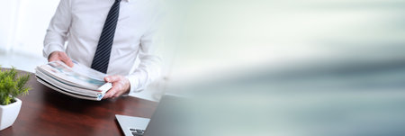 Hands of businessman holding magazines; panoramic bannerの写真素材