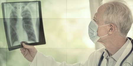 Doctor wearing a medical face mask and examining lungs x-ray during coronavirus outbreak, geometric patternの写真素材