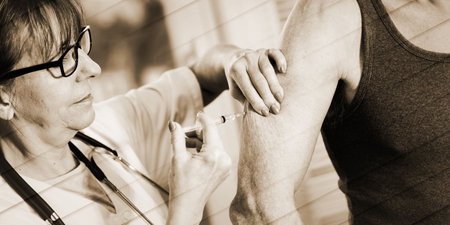 Female doctor injecting vaccine to senior man, geometric patternの写真素材