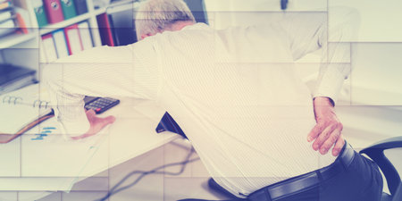 Businessman suffering from back pain at office, geometric patternの写真素材