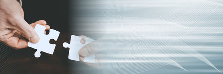 Hands joining two puzzle pieces, teamwork concept; panoramic bannerの写真素材