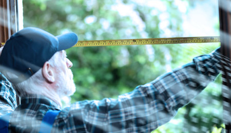 Senior repairman taking measures with tape measure; light-effectの写真素材