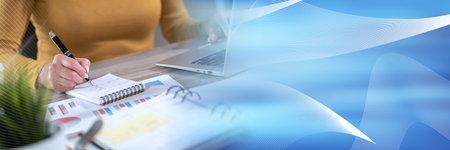 Businesswoman taking notes while using laptop; panoramic banner