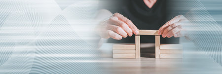 Hands building a wooden block bridge; concept of business associations; panoramic banner