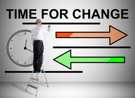 Man on a ladder drawing time for change concept on a wallの写真素材