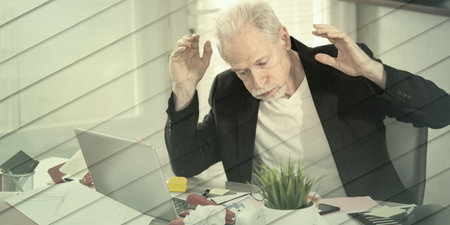 Overworked senior businessman sitting at a messy desk, geometric patternの写真素材