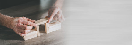 Hands building a wooden block bridge; concept of business associations; panoramic bannerの写真素材