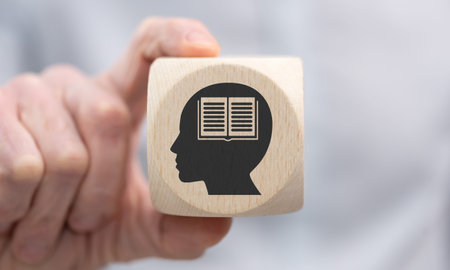 Hand holding a wooden cube with symbol of knowledge conceptの写真素材
