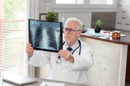 Senior doctor looking at x-ray in medical officeの写真素材