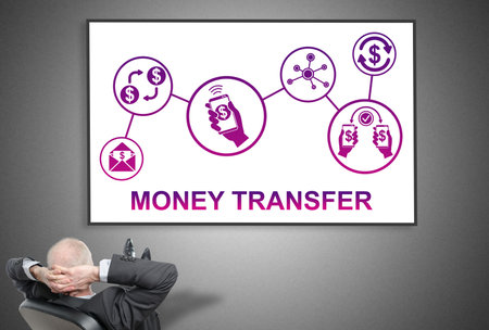 Relaxed businessman looking at money transfer concept on a whiteboardの写真素材