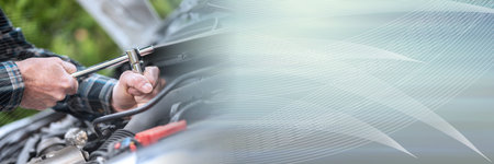 Hands of car mechanic repairing a car engine; panoramic banner