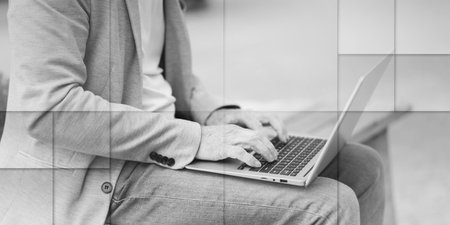 Businessman sitting on a bench outdoors and using laptop, geometric patternの写真素材