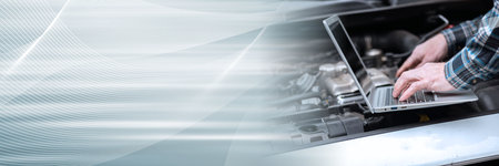 Car mechanic using laptop for checking car engine; panoramic banner