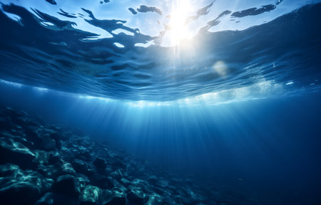 Sunlight streaming through the water's surface, highlighting the rocky seabed in a captivating underwater sceneの素材