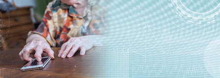 Old woman using smartphone at home; panoramic bannerの写真素材