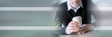 Businessman holding a paper coffee cup during break; panoramic bannerの写真素材