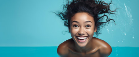 Exuberant young woman laughing, submerged in clear blue water, hair flowingの素材