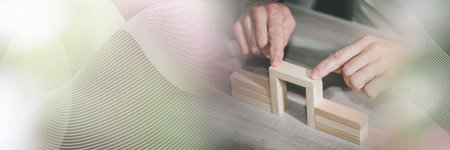 Male hand building a bridge with wooden blocks; concept of association; panoramic banner