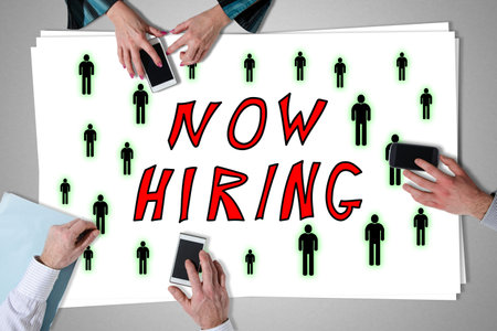 Hiring concept placed on a desk with hands using smartphones