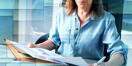 Mature businesswoman checking documents in office, geometric patternの写真素材