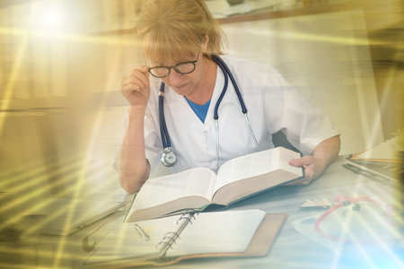 Female doctor reading a textbook in medical office; multiple exposureの写真素材