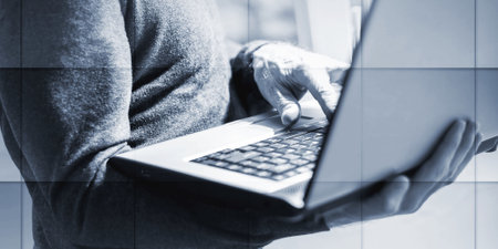 Senior businessman standing and working on his laptop in office, geometric patternの写真素材