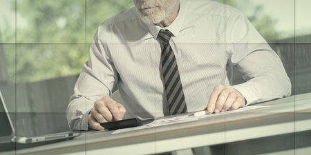 Accountant working on financial documents and using a calculator, geometric patternの写真素材