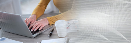 Businesswoman working on laptop in office; panoramic banner