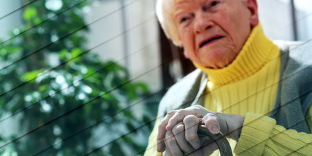Old woman sitting with her hands on a cane, geometric patternの写真素材