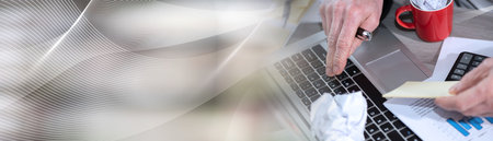 Businessman working on a cluttered and messy desk; panoramic banner