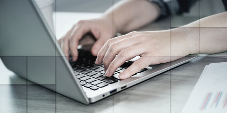 Female hands typing on laptop keyboard, geometric pattern