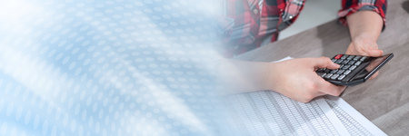 Woman using calculator and working on financial data; panoramic banner