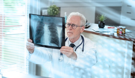 Senior doctor looking at x-ray in medical office; light effect