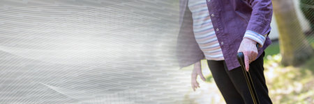 Elderly woman holding a walking stick, outdoors; panoramic banner